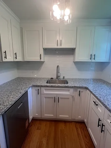 a kitchen with granite countertop wooden cabinets a sink and dishwasher
