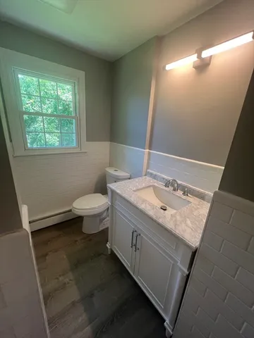 a bathroom with a granite countertop sink a toilet a mirror and a window