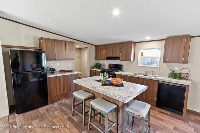 a kitchen with stainless steel appliances granite countertop a refrigerator a stove a sink a dining table and chairs