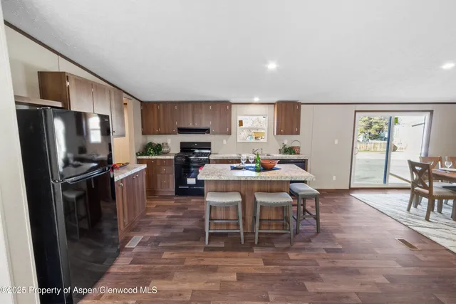 a kitchen with stainless steel appliances a refrigerator a stove a dining table and chairs