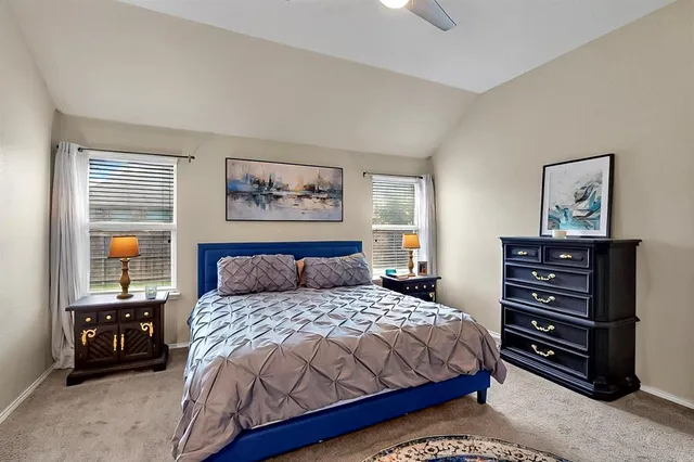 a bedroom with a bed a dresser and painting