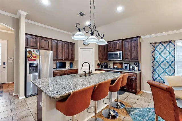 a kitchen with stainless steel appliances granite countertop a sink dishwasher a dining table and chairs with wooden floor