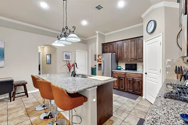 a kitchen with stainless steel appliances granite countertop a stove a sink dishwasher a dining table and chairs with wooden floor