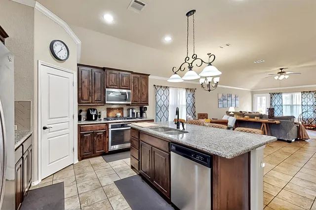a kitchen with stainless steel appliances granite countertop a kitchen island a stove and a sink