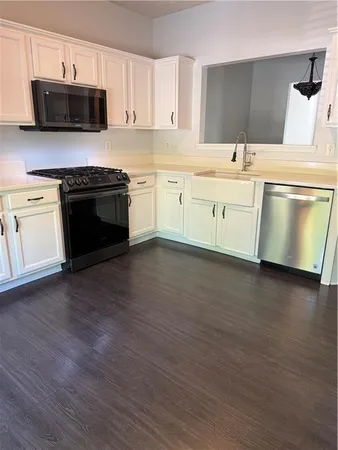 a kitchen with stainless steel appliances a stove a sink and white cabinets