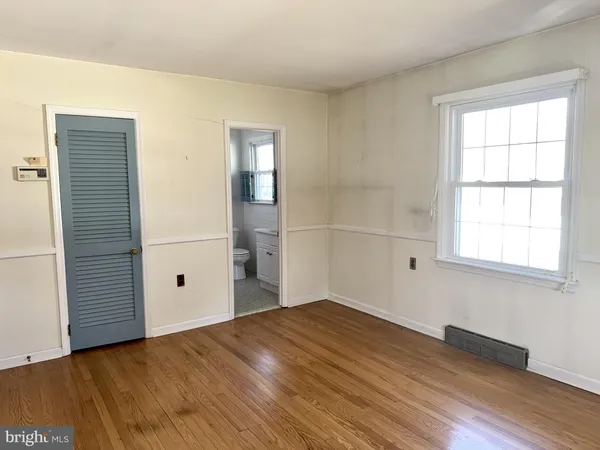 an empty room with wooden floor closet and windows