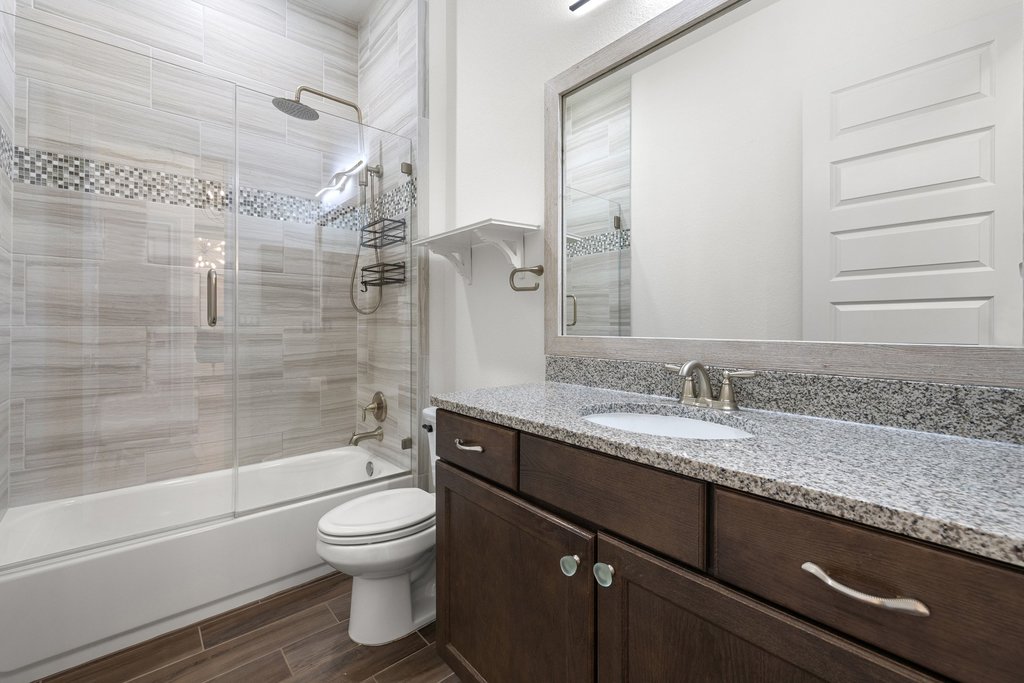 17641 Stratus Cove Dripping Springs, TX 78620 - Photo 27 of 40 a bathroom with a granite countertop sink toilet a mirror and shower