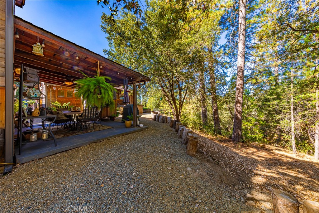 5757 Clouds Rest Mariposa, CA 95338 - Photo 47 of 68 a view of a patio with table and chairs under an umbrella with barbeque grill and plants