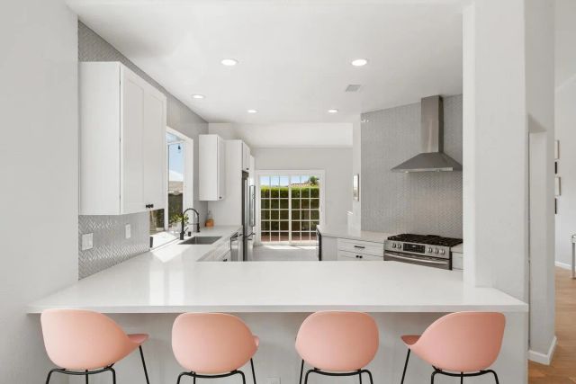 a large white kitchen with a stove a sink dishwasher a refrigerator and white cabinets with wooden floor