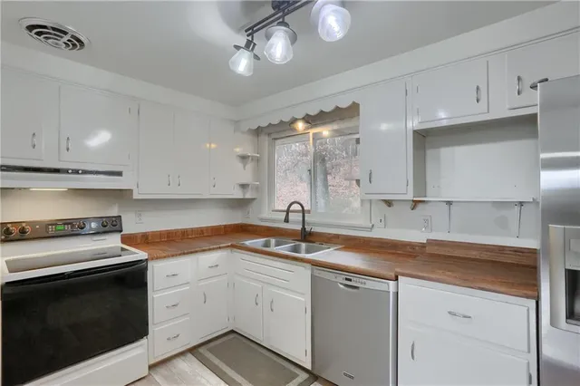 a kitchen with a sink dishwasher and white cabinets