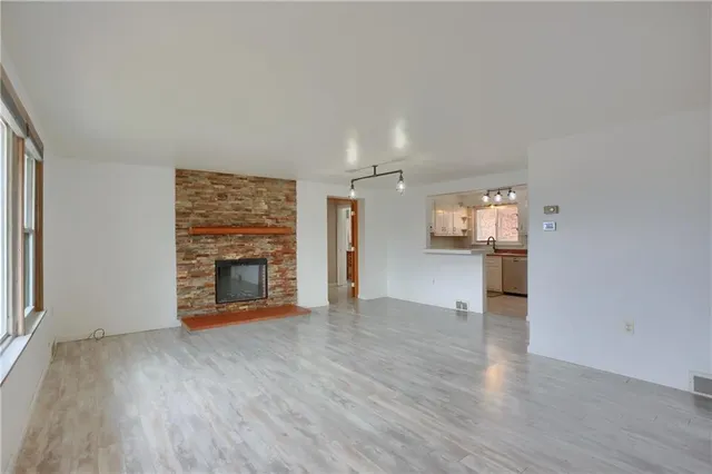 an empty room with wooden floor fireplace and windows