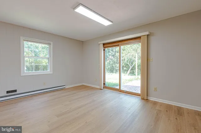 an empty room with wooden floor and windows