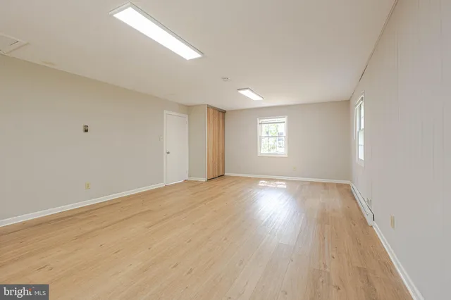 an empty room with wooden floor and windows