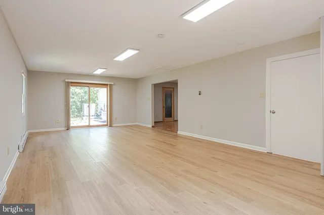 a view of an empty room with wooden floor and window