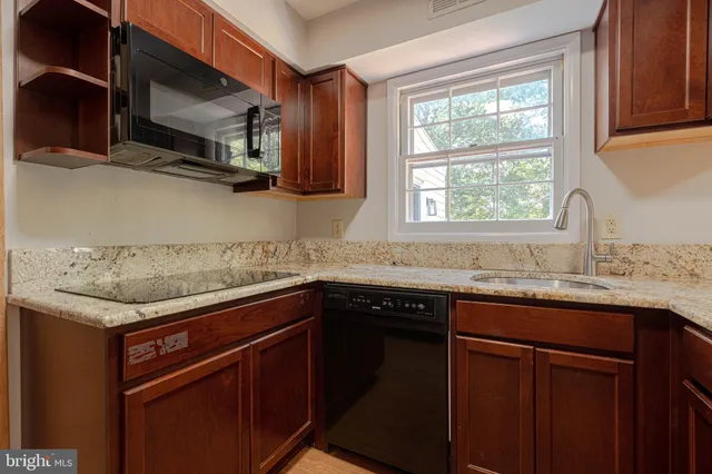 a kitchen with stainless steel appliances granite countertop a sink a stove a microwave and wooden cabinets