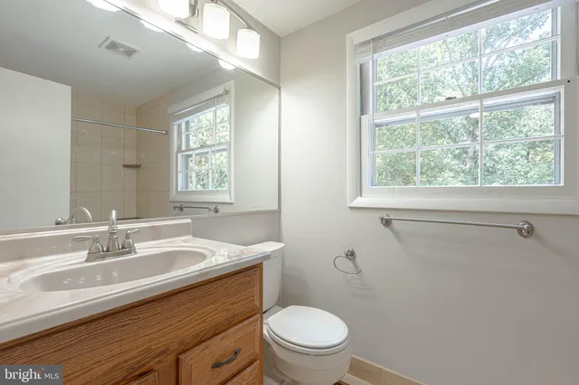 a bathroom with a sink a mirror a toilet and a window