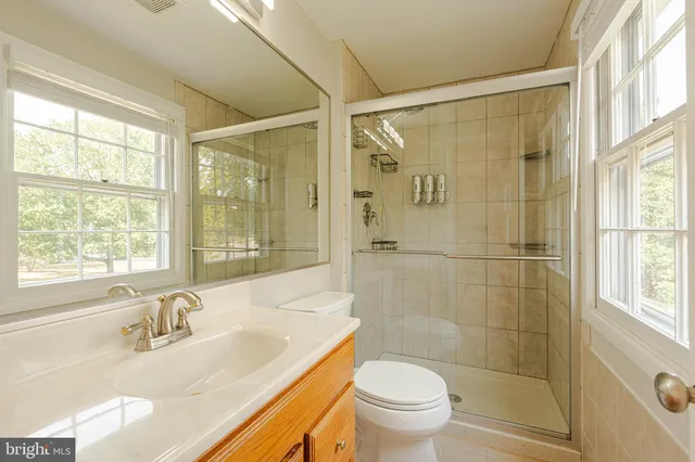 a bathroom with a granite countertop sink a toilet and shower