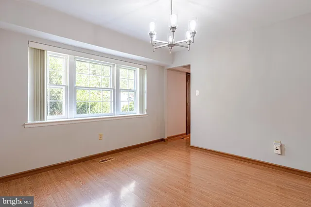 a view of empty room with wooden floor fan and window