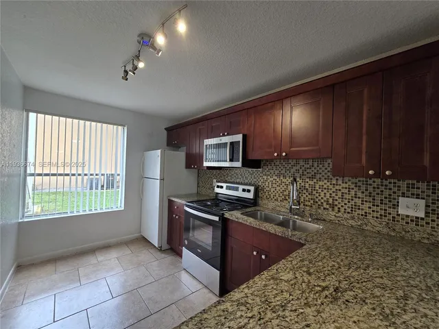 a kitchen with stainless steel appliances granite countertop a stove a sink and a microwave