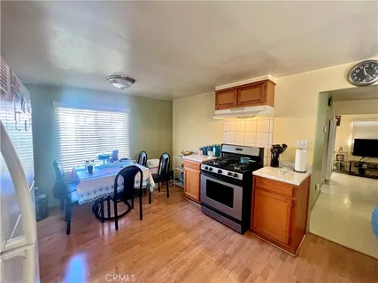 a kitchen with stainless steel appliances granite countertop a stove top oven a sink dishwasher and a dining table with wooden floor