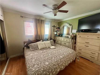 a bedroom with a large bed and a flat tv screen on dresser