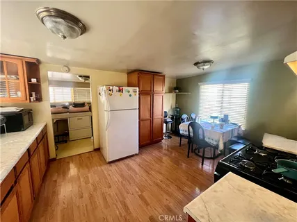 a kitchen with stainless steel appliances granite countertop a refrigerator a stove a sink dishwasher and a dining table with wooden floor