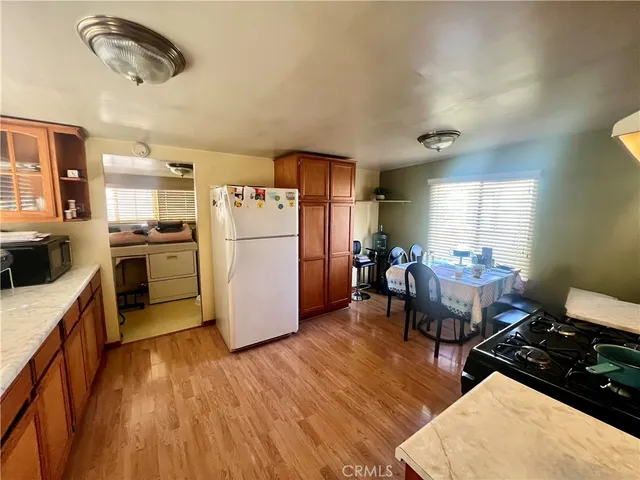 a kitchen with stainless steel appliances granite countertop a refrigerator a stove a sink dishwasher and a dining table with wooden floor