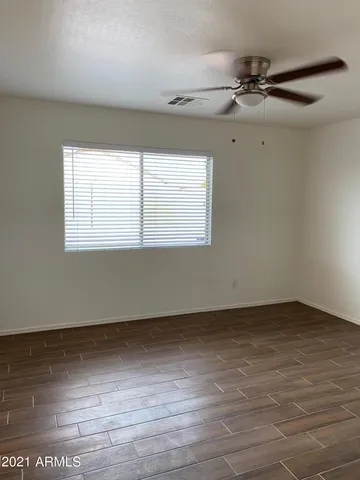 an empty room with wooden floor fan and windows