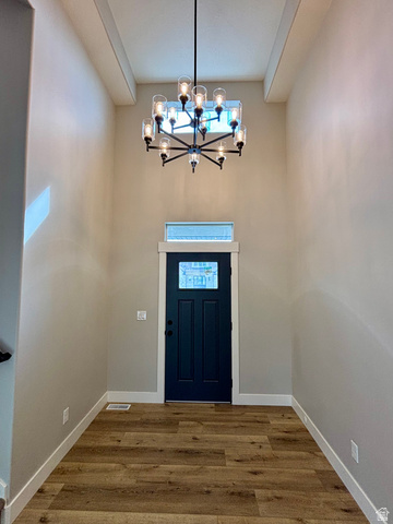 1184 West 3250 North Ogden, UT 84414 - Photo 21 of 69 Two-story entry featuring wood-finish flooring, a dark blue paneled door with upper glass paneling, a transom window, and a twelve-light chandelier