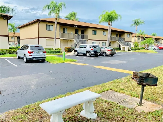 a front view of a building with cars parked