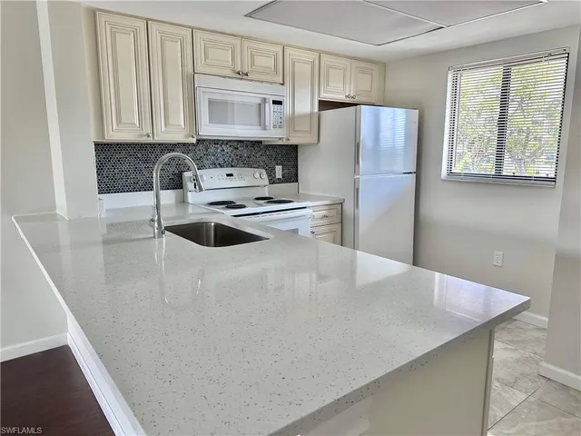 a kitchen with stainless steel appliances a refrigerator a stove a sink a center island and a refrigerator