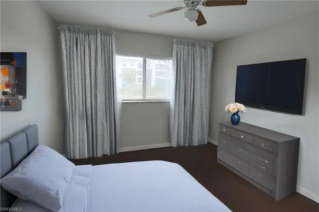 a bedroom with a bed and a flat tv screen on the dresser