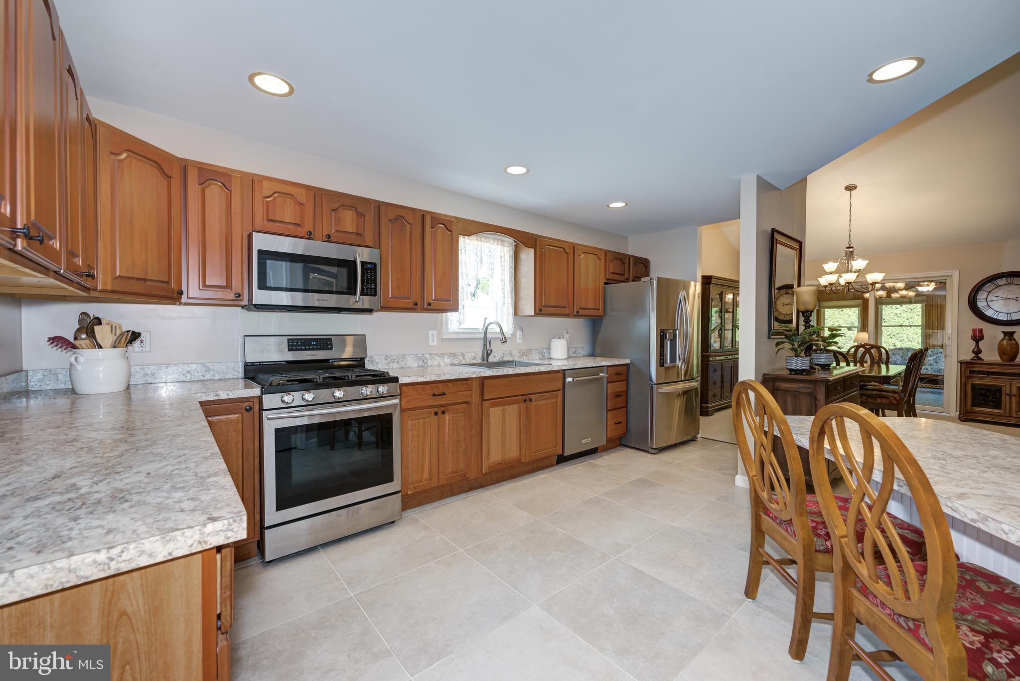 137 Skipper Road Manahawkin, NJ 08050 - Photo 14 of 33 a kitchen with stainless steel appliances granite countertop a stove top oven a sink dishwasher a dining table and chairs with wooden floor