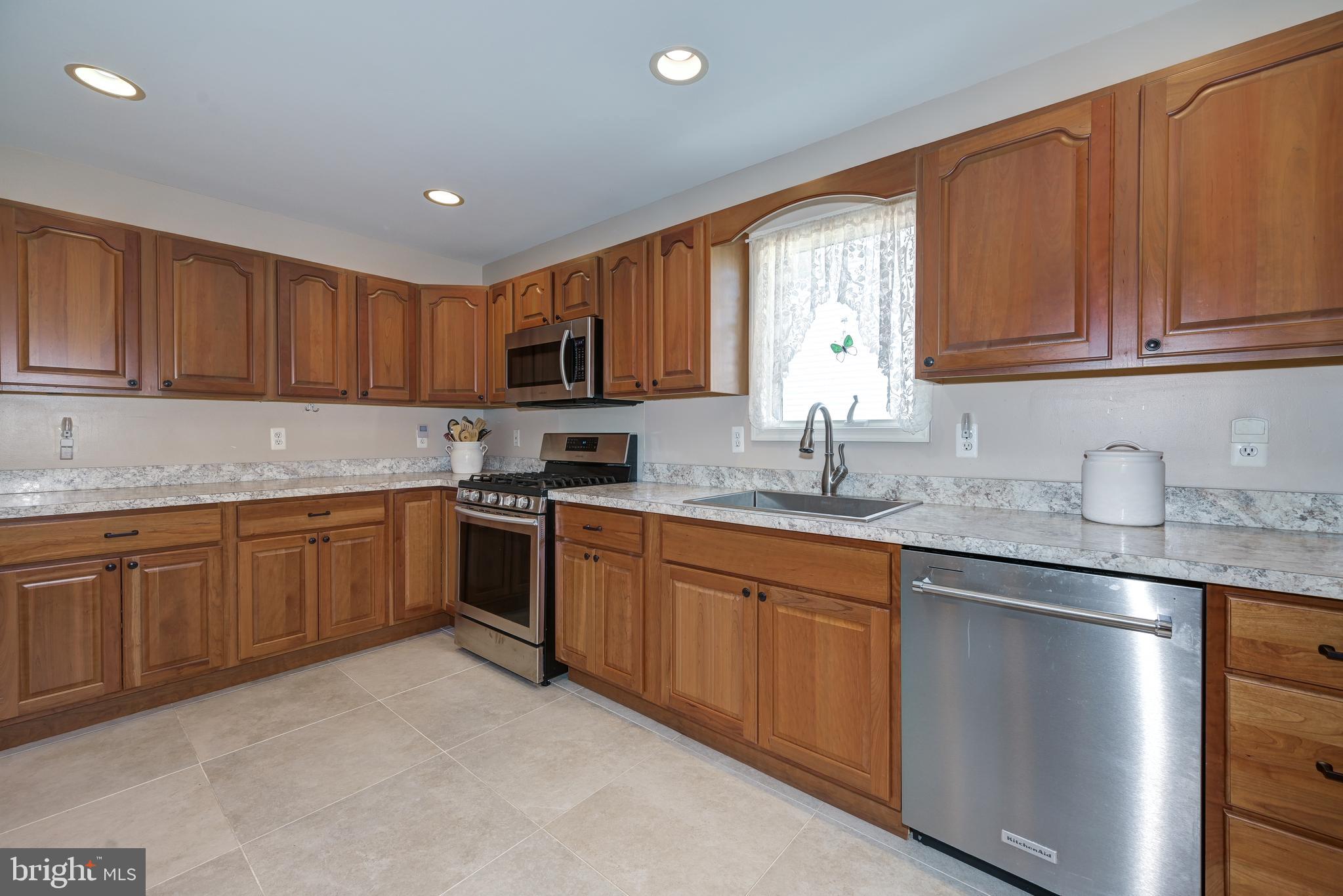137 Skipper Road Manahawkin, NJ 08050 - Photo 15 of 33 a kitchen with granite countertop wooden cabinets a sink a stove a window and stainless steel appliances