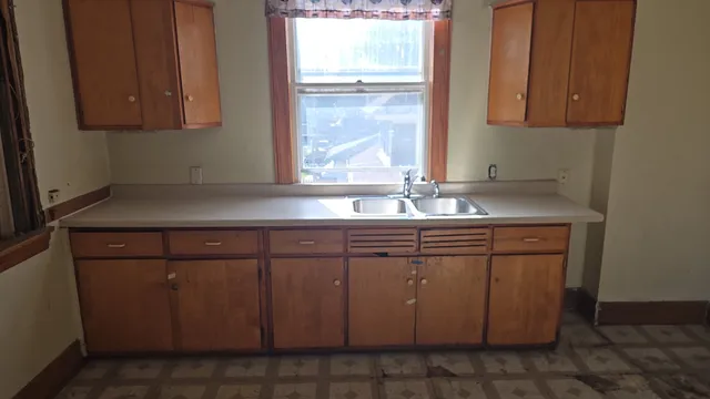 a sink with granite countertop cabinets and window