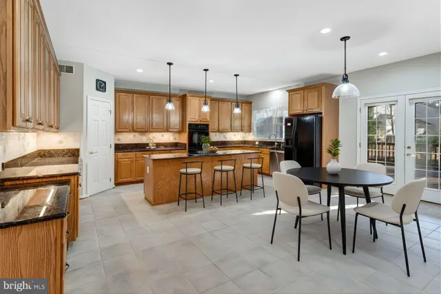 a kitchen with stainless steel appliances granite countertop a stove a refrigerator a oven a sink with a dining table and chairs