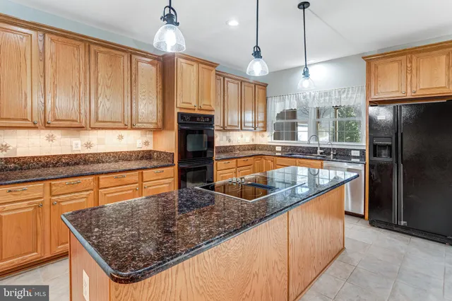 a kitchen with stainless steel appliances granite countertop a sink a refrigerator and wooden cabinets