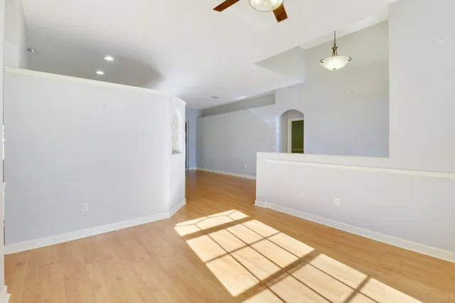 a view of empty room with wooden floor and fan