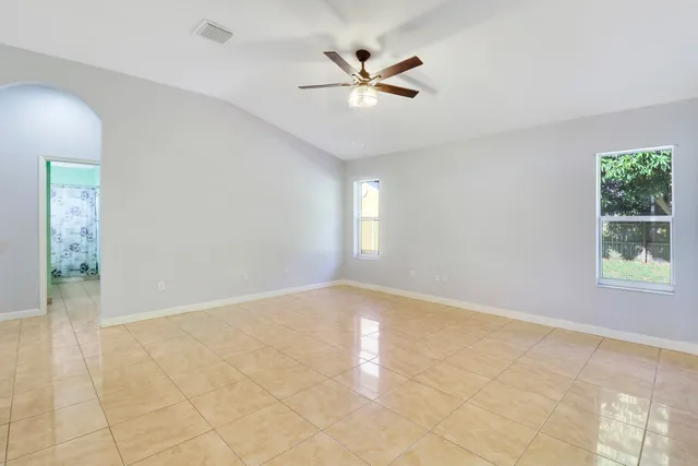 an empty room with windows and ceiling fan