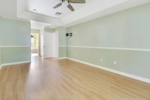 an empty room with wooden floor and ceiling fan