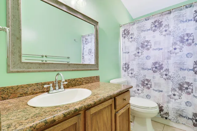 a bathroom with a granite countertop sink mirror vanity and toilet
