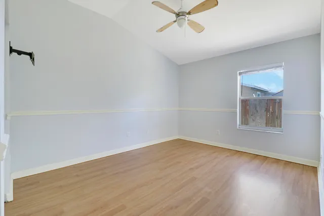 an empty room with wooden floor closet and fan