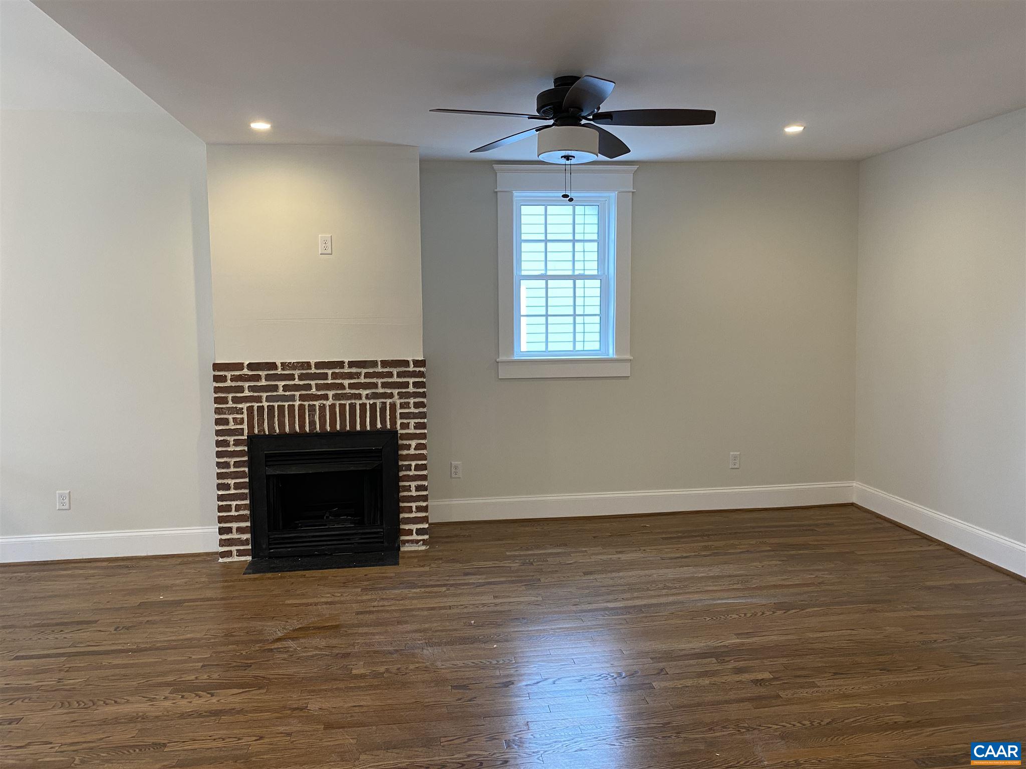 1928 Lewis Mountain Road, Unit B Charlottesville, VA 22903 - Photo 17 of 22 a view of an empty room with wooden floor fireplace and a window