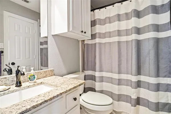 a bathroom with a granite countertop sink a toilet and a mirror