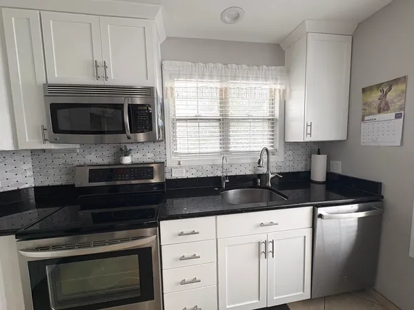 a kitchen with granite countertop a stove a microwave a sink and cabinets