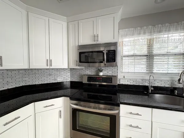 a kitchen with granite countertop white cabinets and black appliances