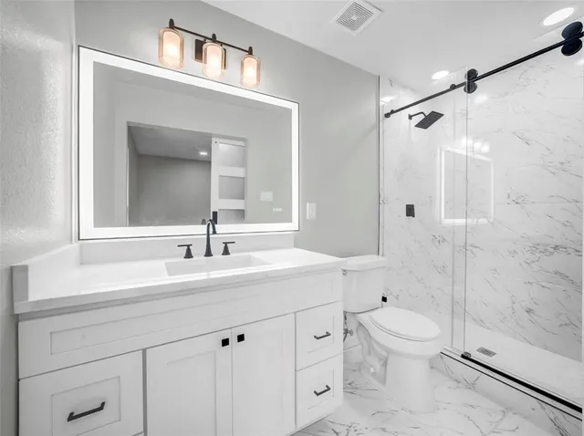 a bathroom with a sink a toilet and shower