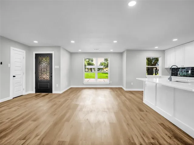 a view of an empty room with window and wooden floor