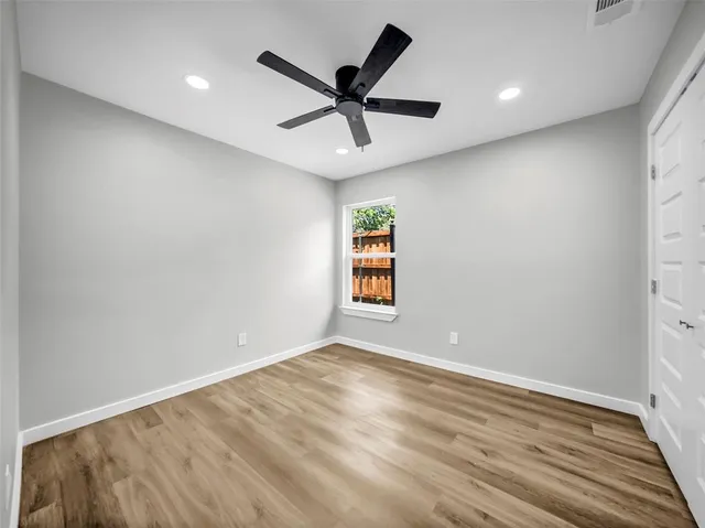 an empty room with wooden floor and ceiling fan