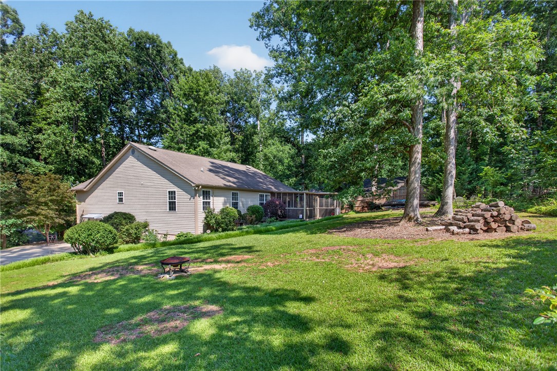 151 Towne Creek Trail Anderson, SC 29621 - Photo 47 of 49 A well-maintained ranch-style home nestled amidst mature trees, offering a tranquil outdoor living space.